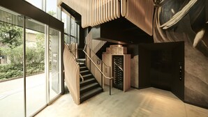 A modern interior with a staircase, a large sculpture, and a view of greenery outside.