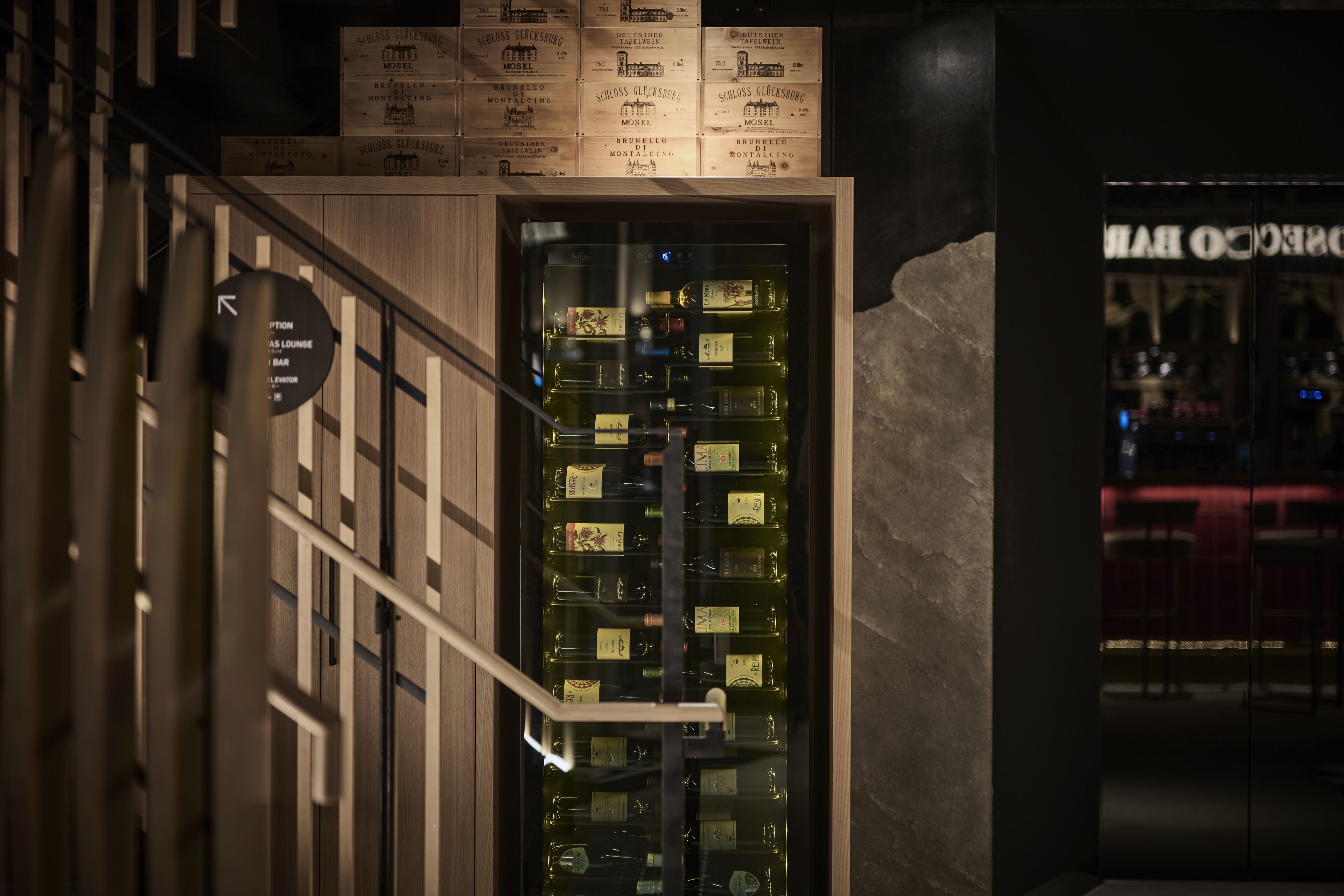 A bar area with a wooden counter and a display of liquor bottles.