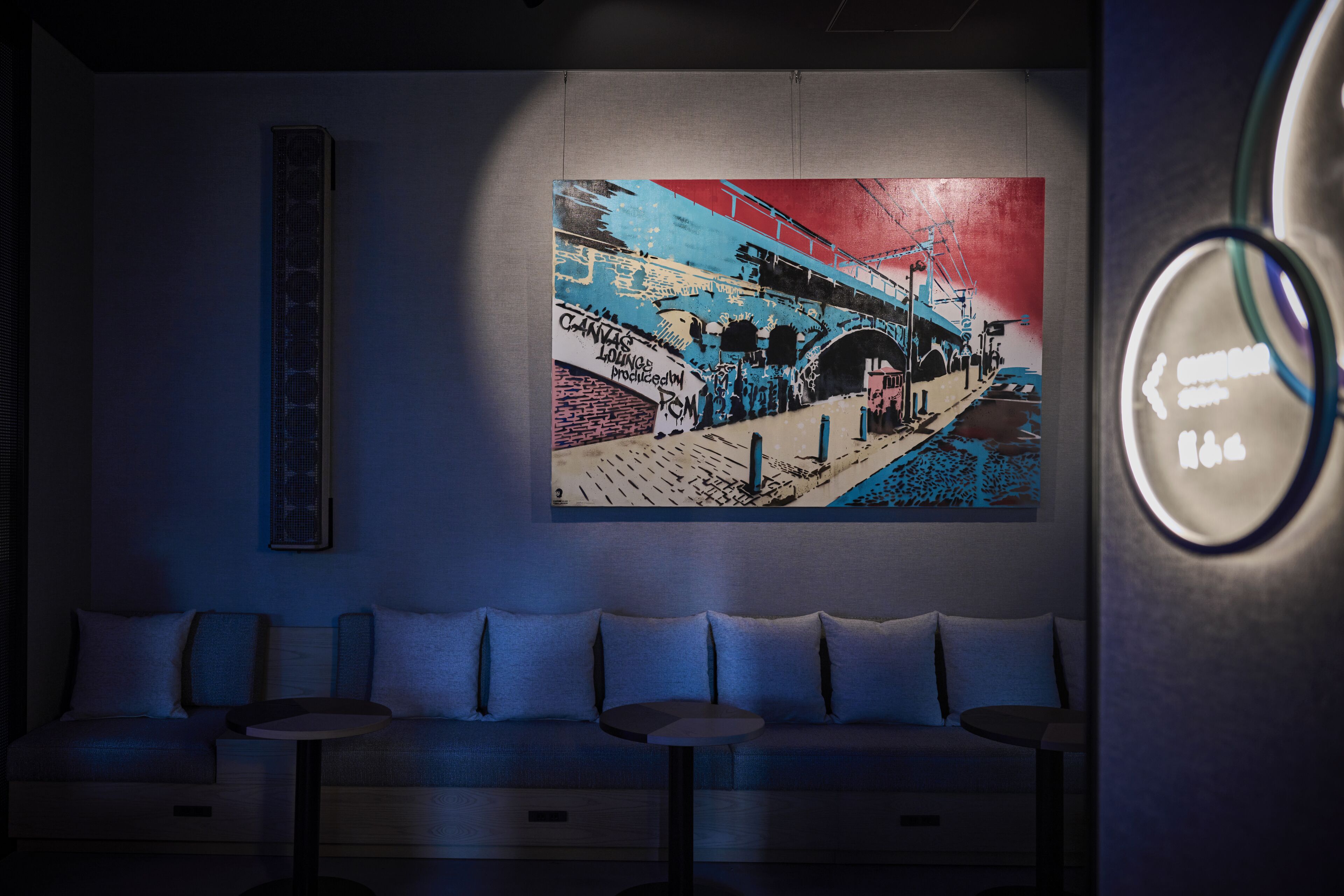 A modern lounge area with a mural, seating, and a digital information display.