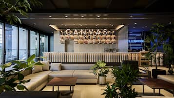 A modern bar area with a neon sign reading "CANVAS" and a seating area with sofas and tables.