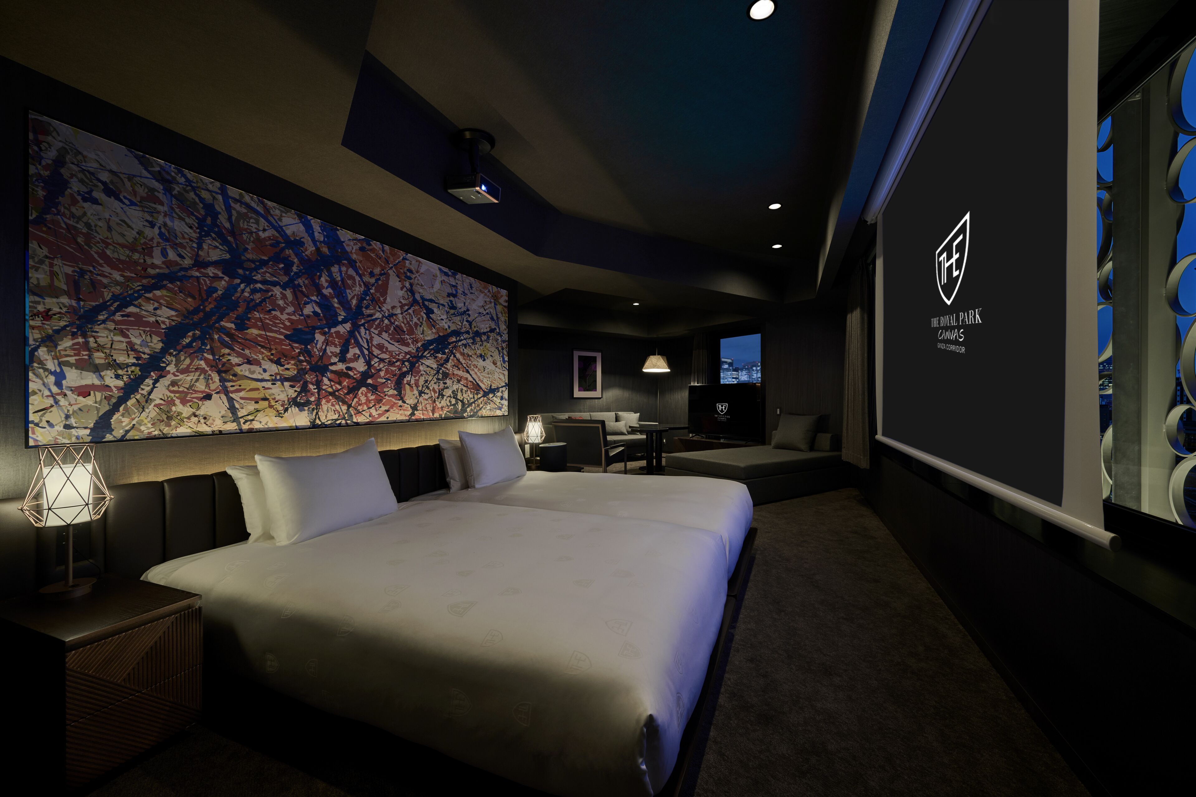 Une chambre d’hôtel moderne, dotée d’un grand lit, d’un bureau, d’une chaise et d’un grand tableau abstrait accroché au mur.