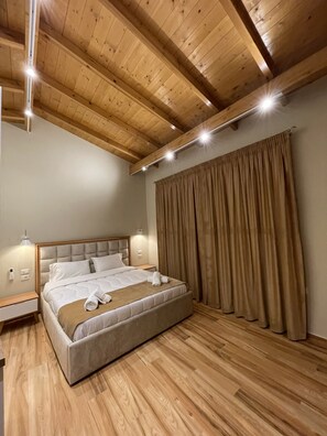 A bedroom with a wooden ceiling, a large bed, a nightstand, and a curtain.