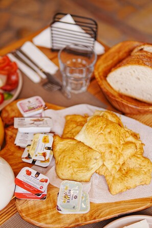 A wooden tray with food items, including bread, butter, and condiments.