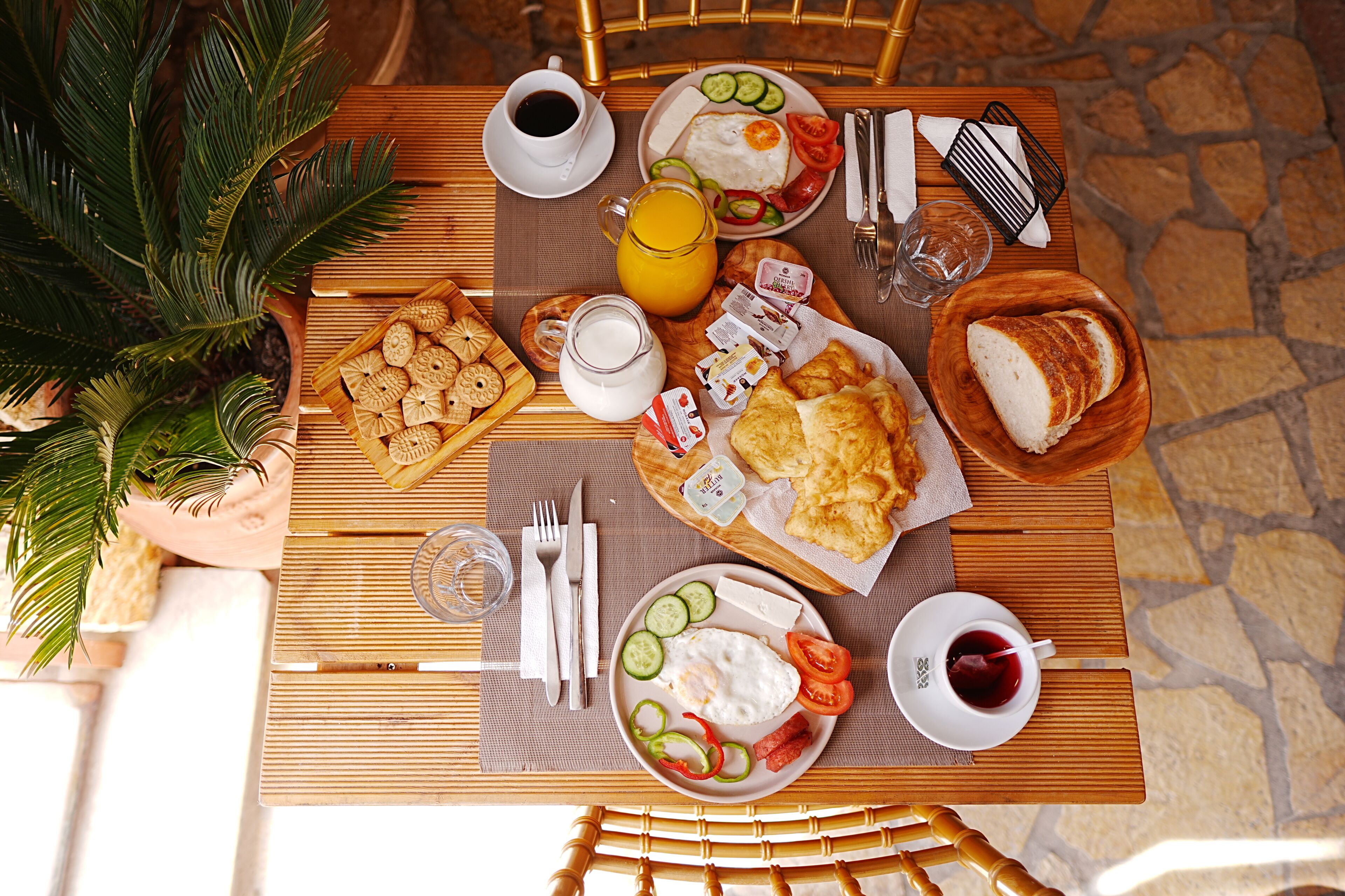 A breakfast table with various food items, a coffee cup, and a glass of juice.