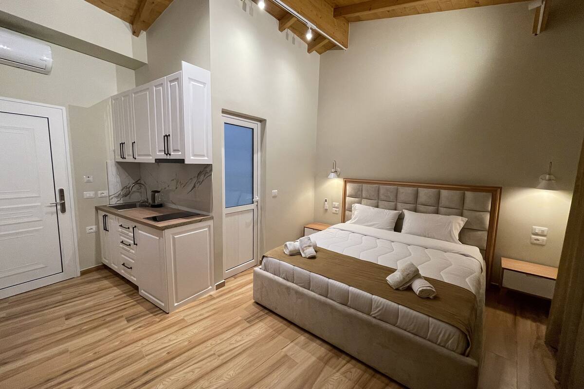 Ein kleines Schlafzimmer mit Bett, Nachttisch und einer kleinen Küchenzeile mit Schränken und einer Arbeitsplatte.