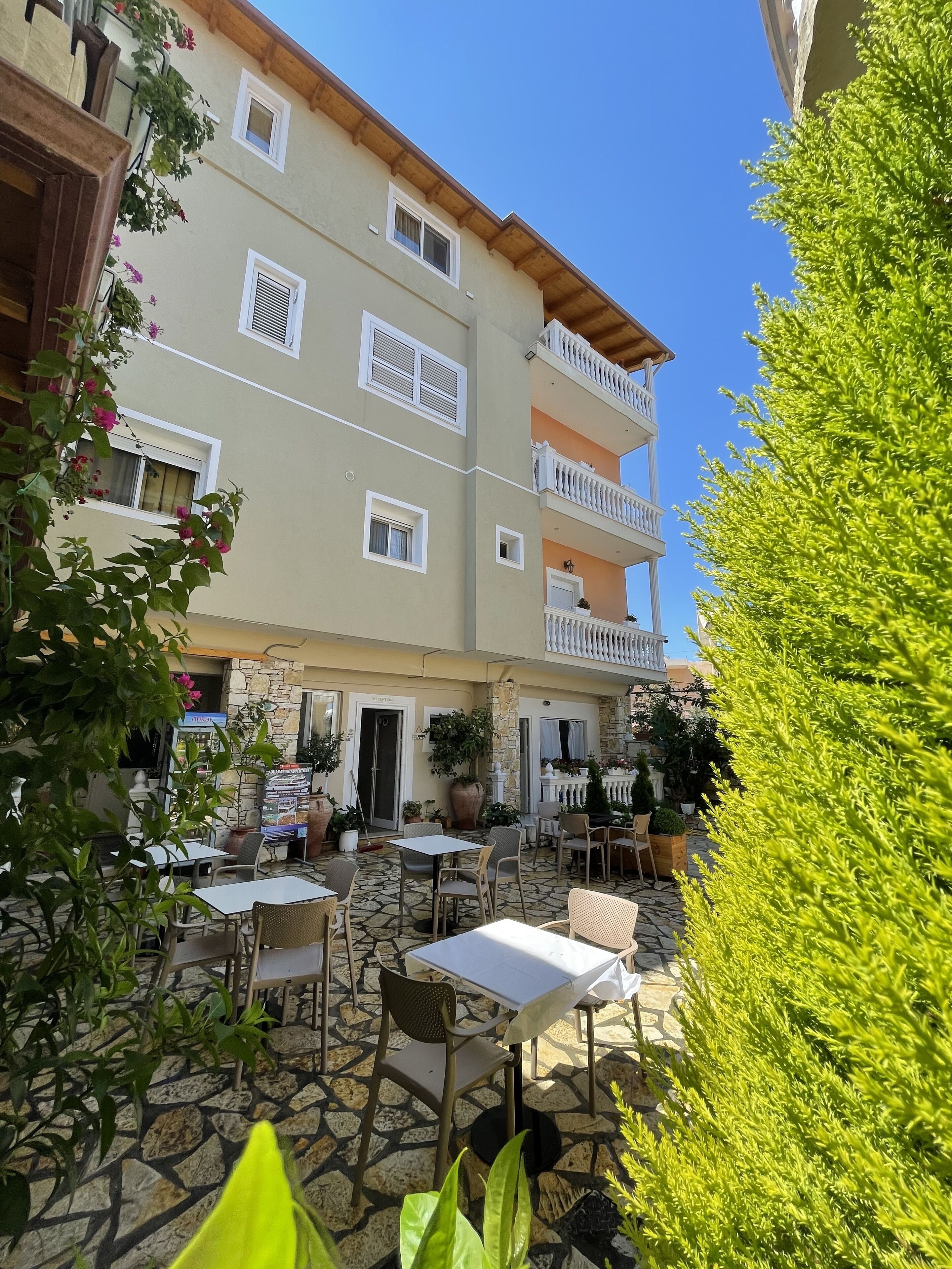 A building with multiple balconies, outdoor seating, and potted plants.