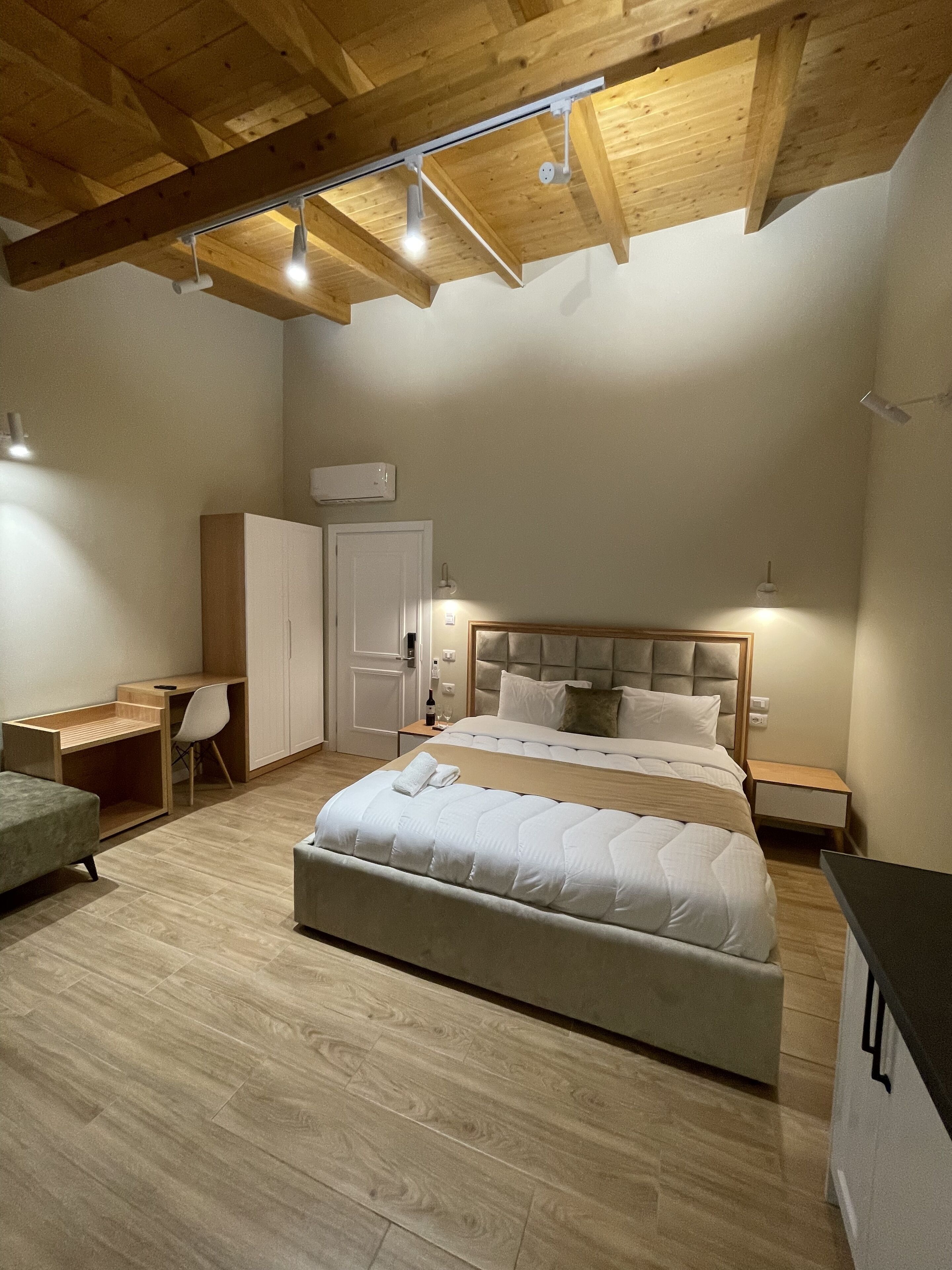A bedroom with a bed, bedside tables, a desk, and a wardrobe.