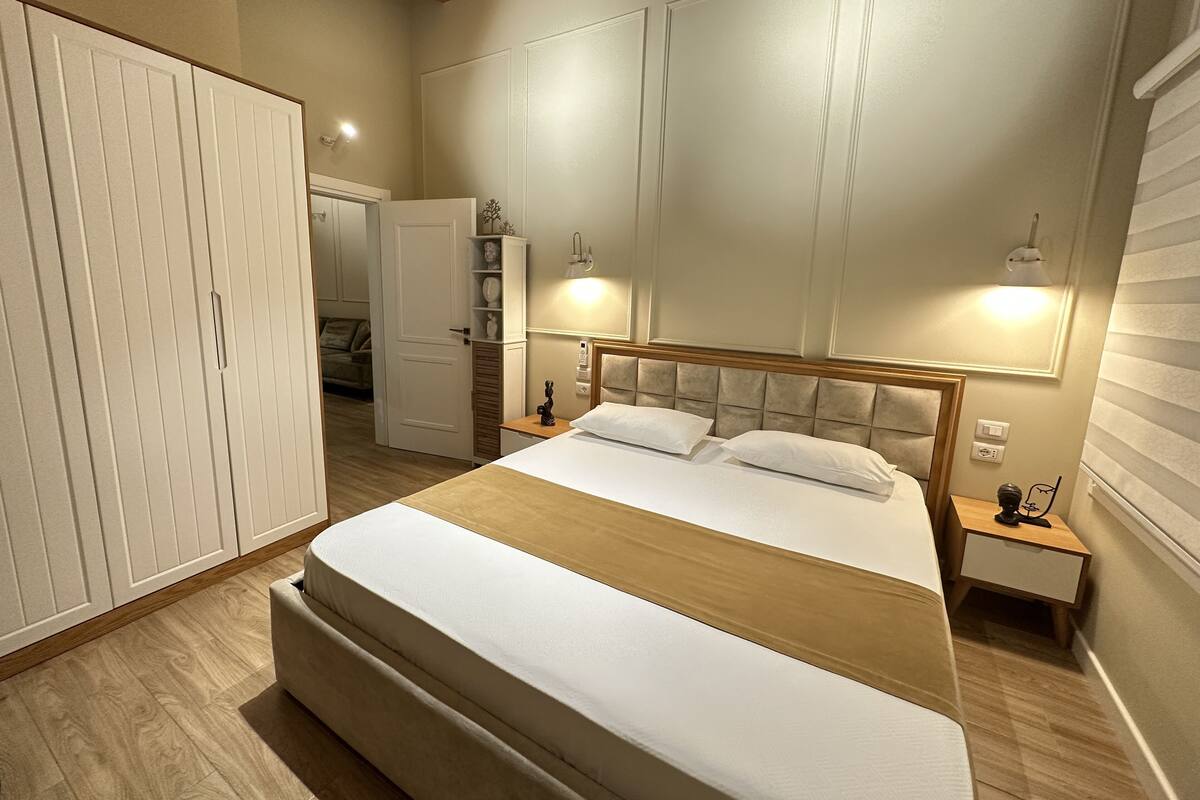 Ein Schlafzimmer mit einem großen Bett, einem Kleiderschrank, einem Nachttisch und einem Spiegel.