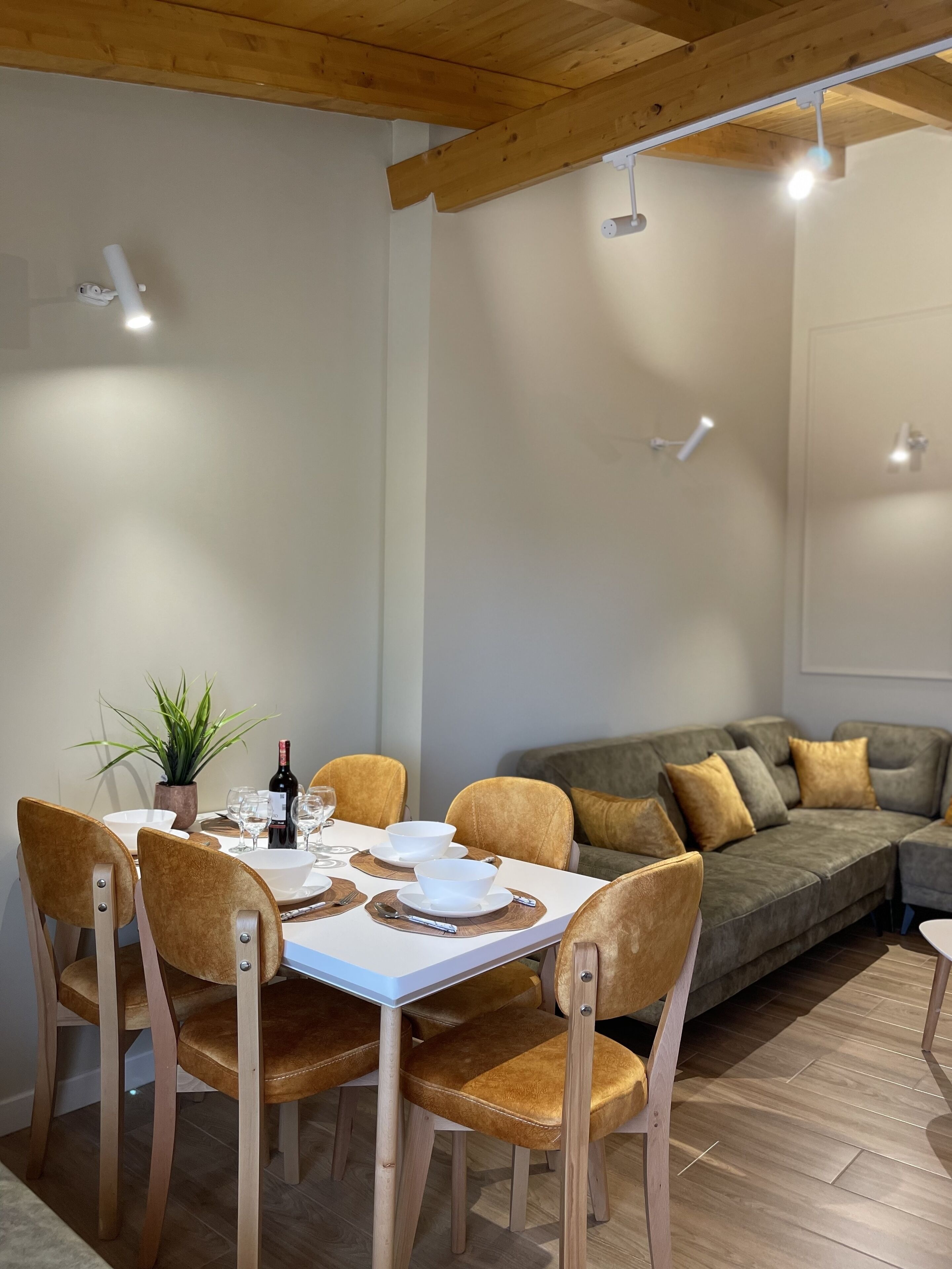 Un coin repas avec une table blanche, des chaises marron et un canapé gris.