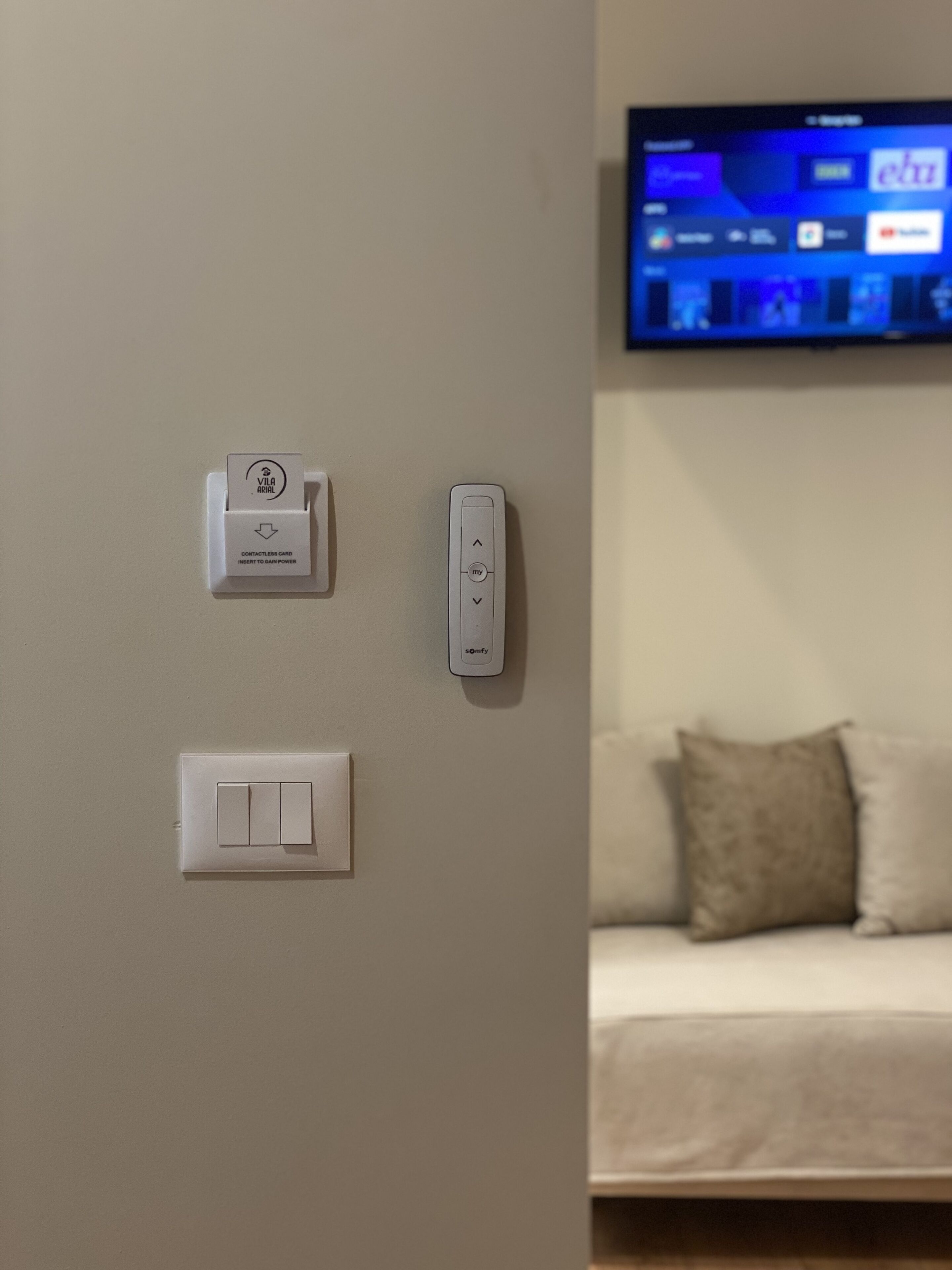 Un lecteur de cartes sans contact fixé au mur, un thermostat intelligent et un interrupteur.