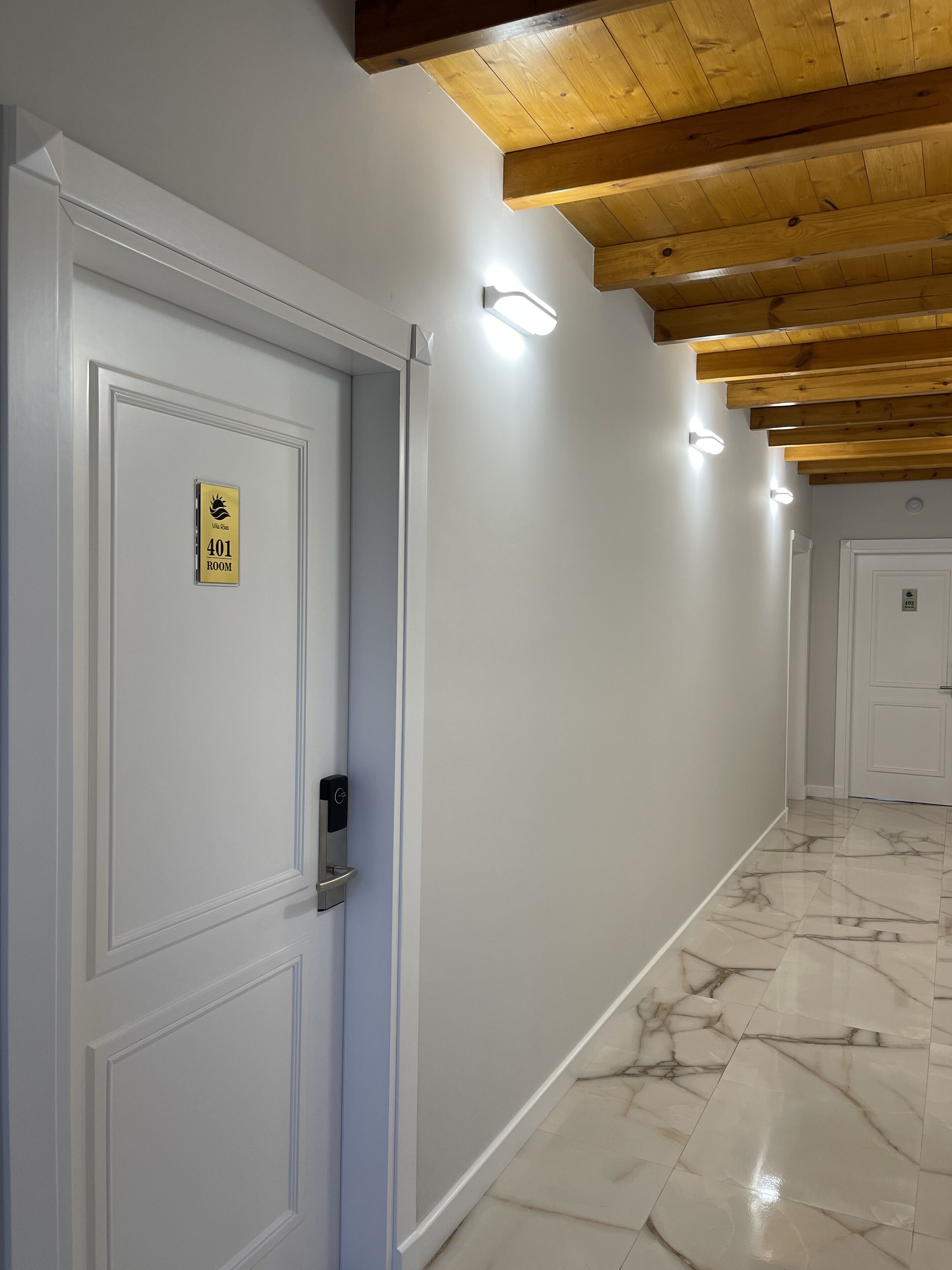 A hallway with a marble floor, white walls, and wooden ceiling beams. A door with a '401 ROOM' sign is visible.