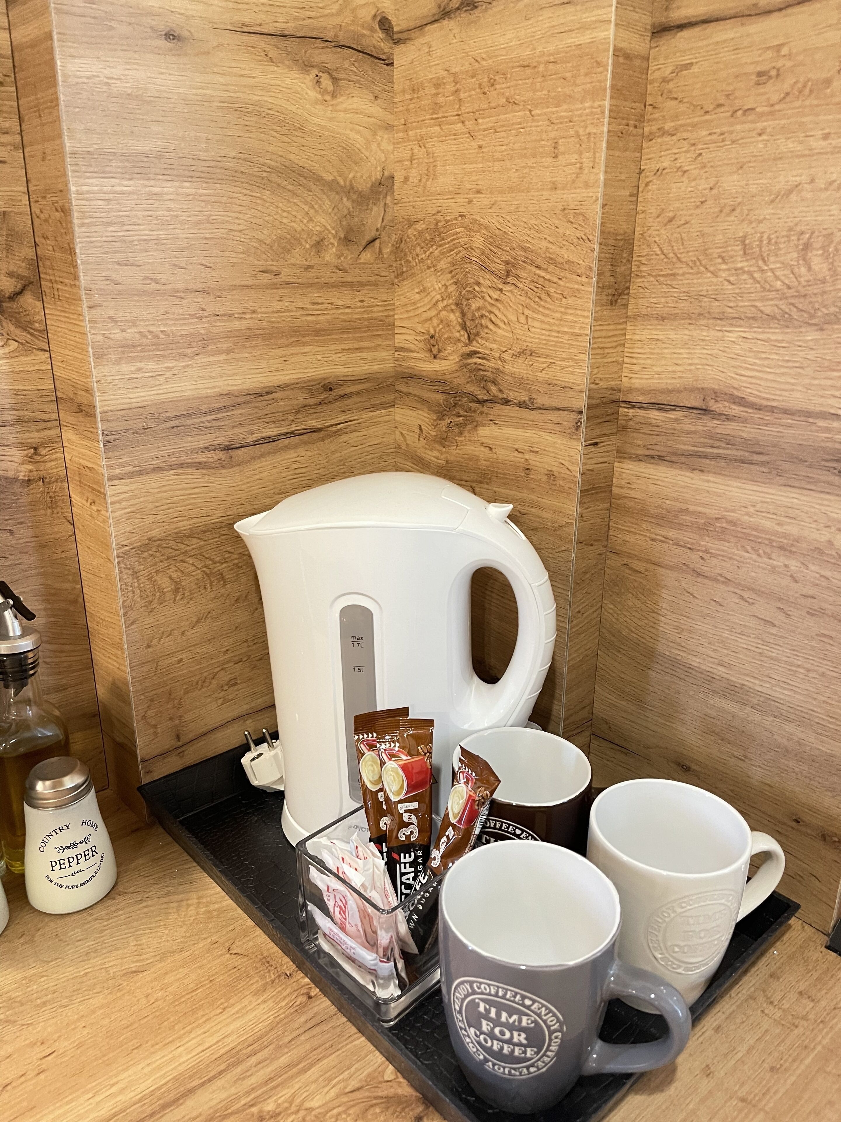 Een kitchenette met een koffiezetapparaat, koffiecups en mokken op een dienblad.