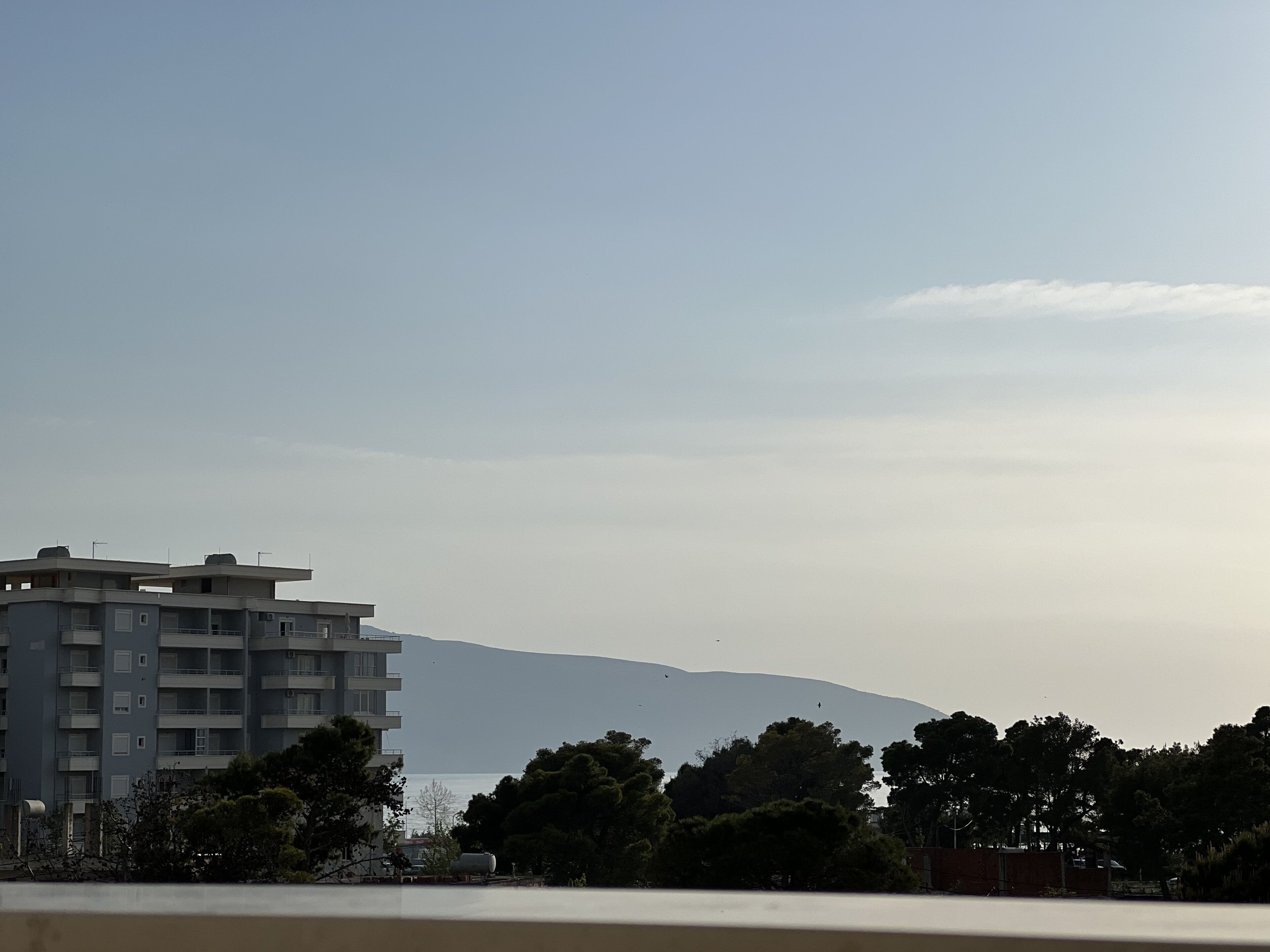 Ein mehrstöckiges Gebäude mit Balkonen, blauem Himmel und einem fernen Berg.