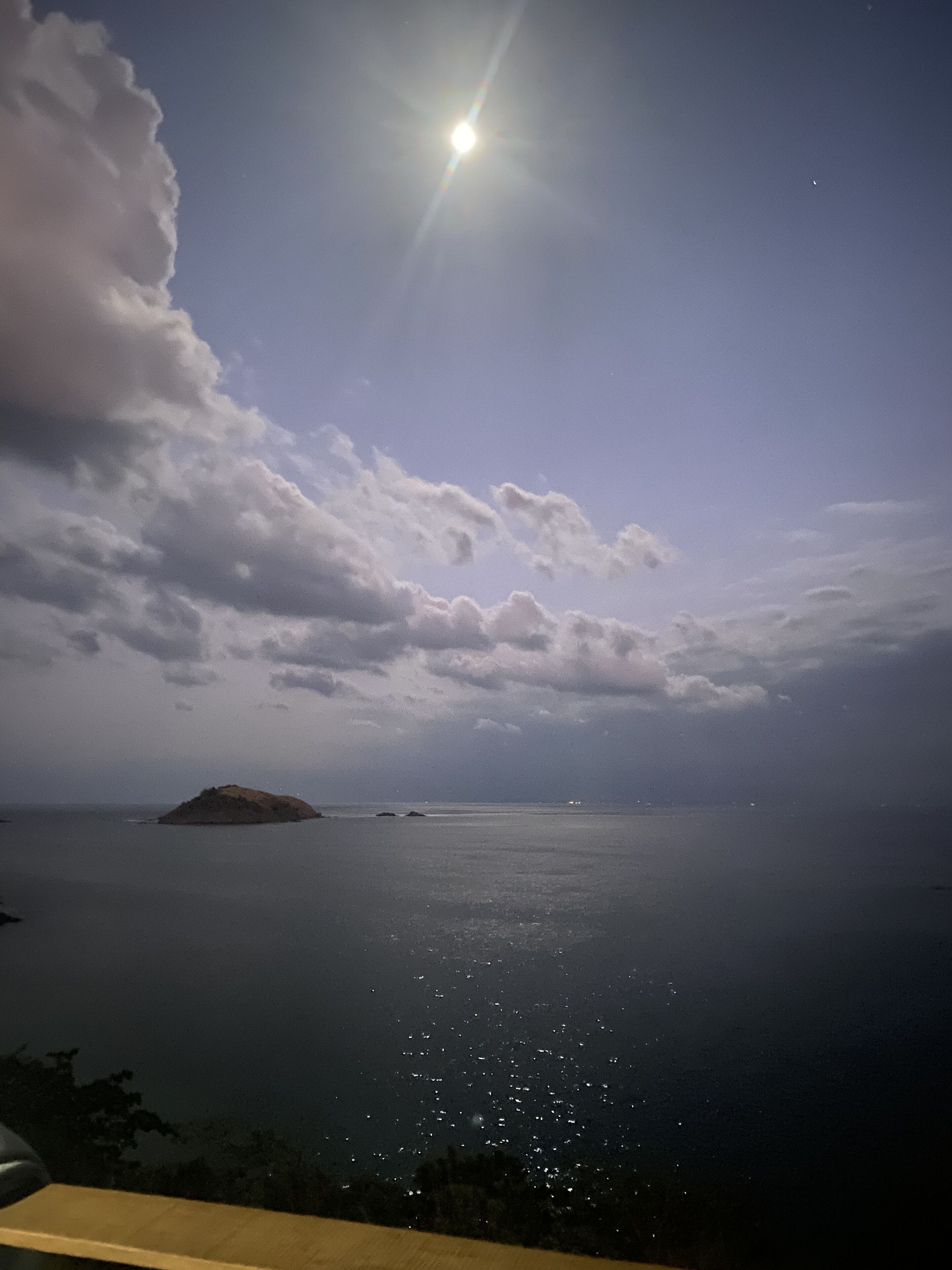 Udsigt over kysten med klar himmel, fuldmåne og roligt hav.