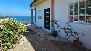 A house with a view of the ocean, a heart-shaped sculpture, and potted plants.
