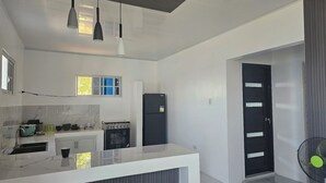 A modern kitchen with a central island, a stove, a refrigerator, and pendant lighting.