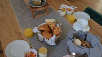 Et morgenbord med croissanter, brød og en skål med frugt.