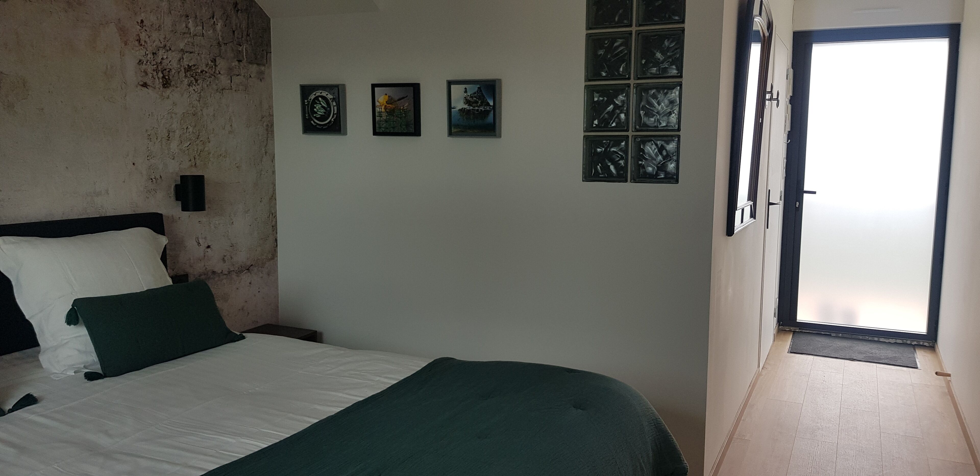 Un dormitorio con cama, una lámpara de pared y una puerta que da a un balcón.