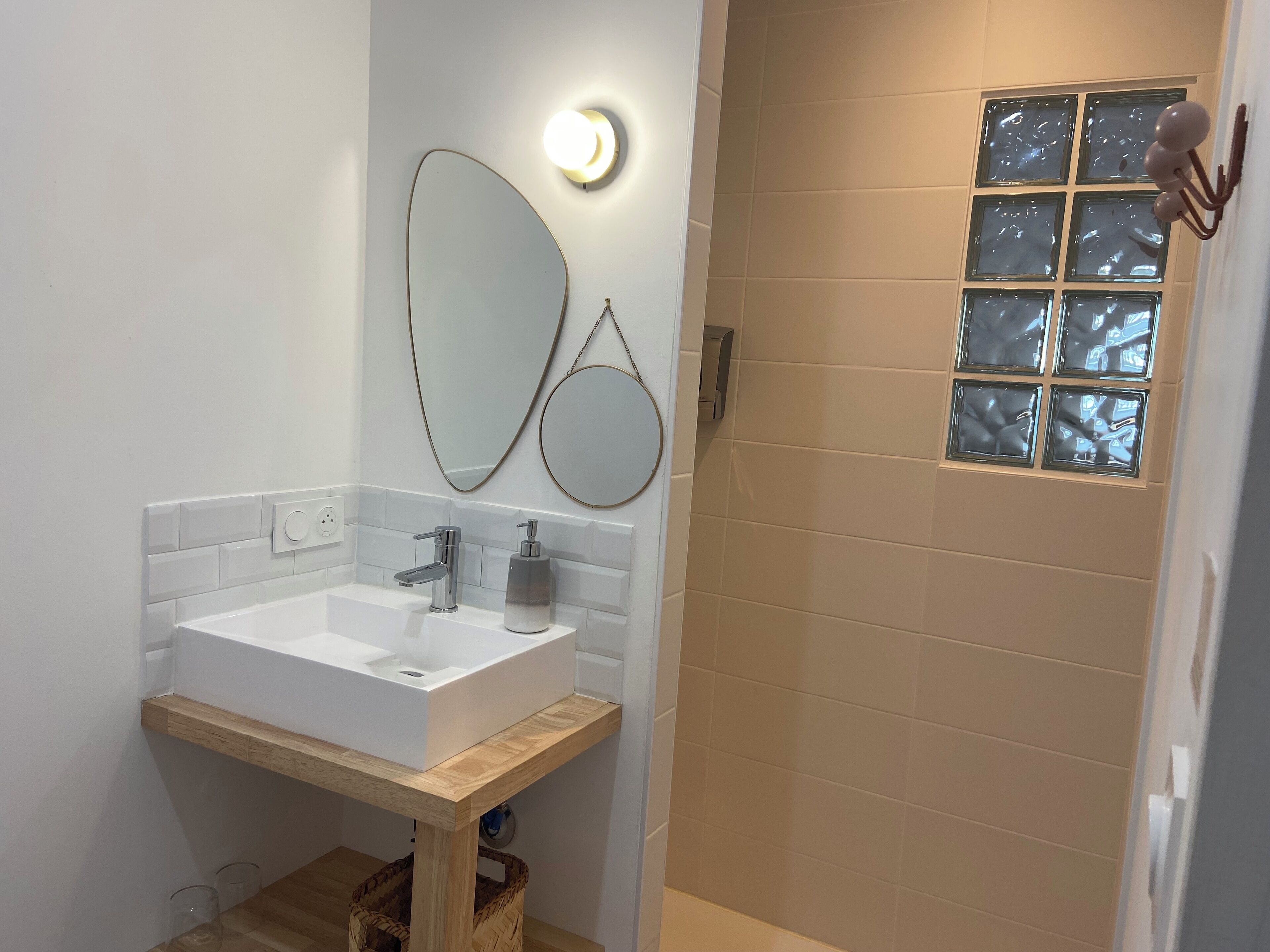 Un baño moderno con un lavabo blanco, un espejo y una zona de ducha con puerta de cristal.