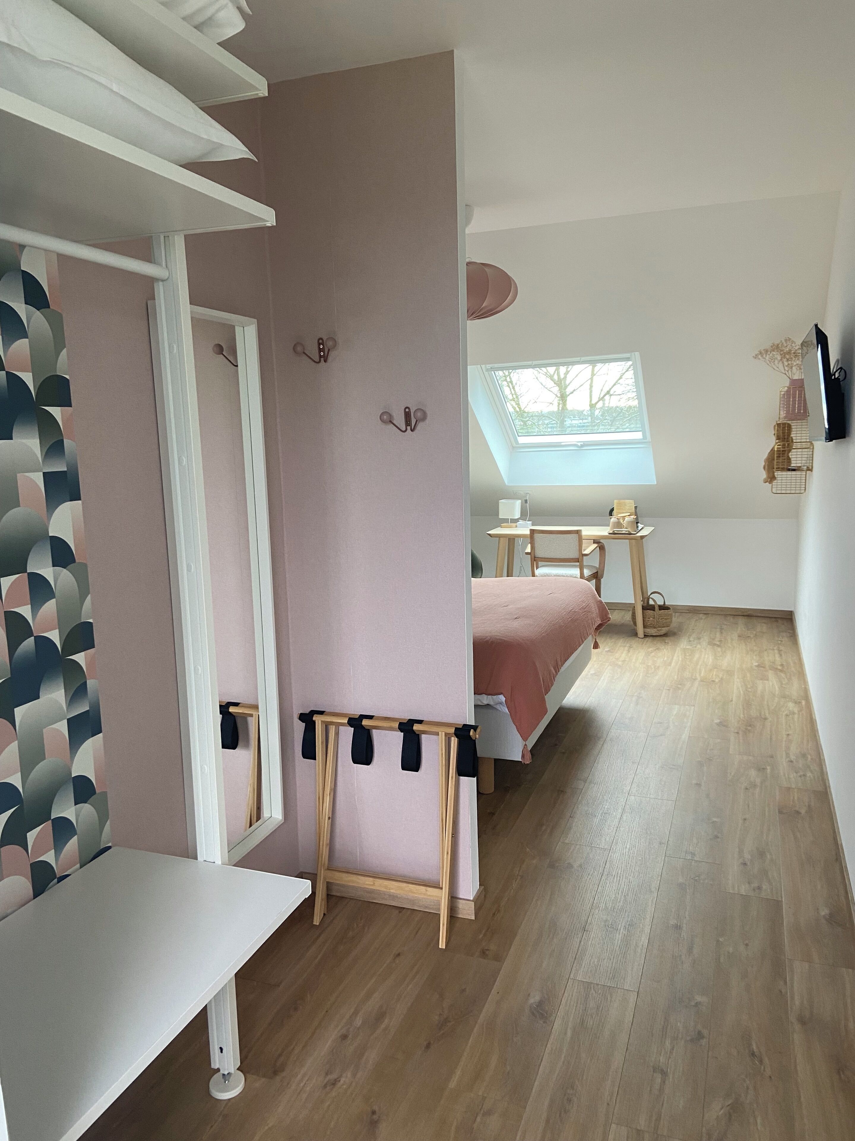 Un dormitorio con cama, escritorio, silla, ventana y tragaluz.