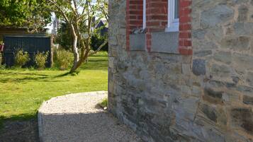 A stone building with a red window and a gravel path leading to it.
