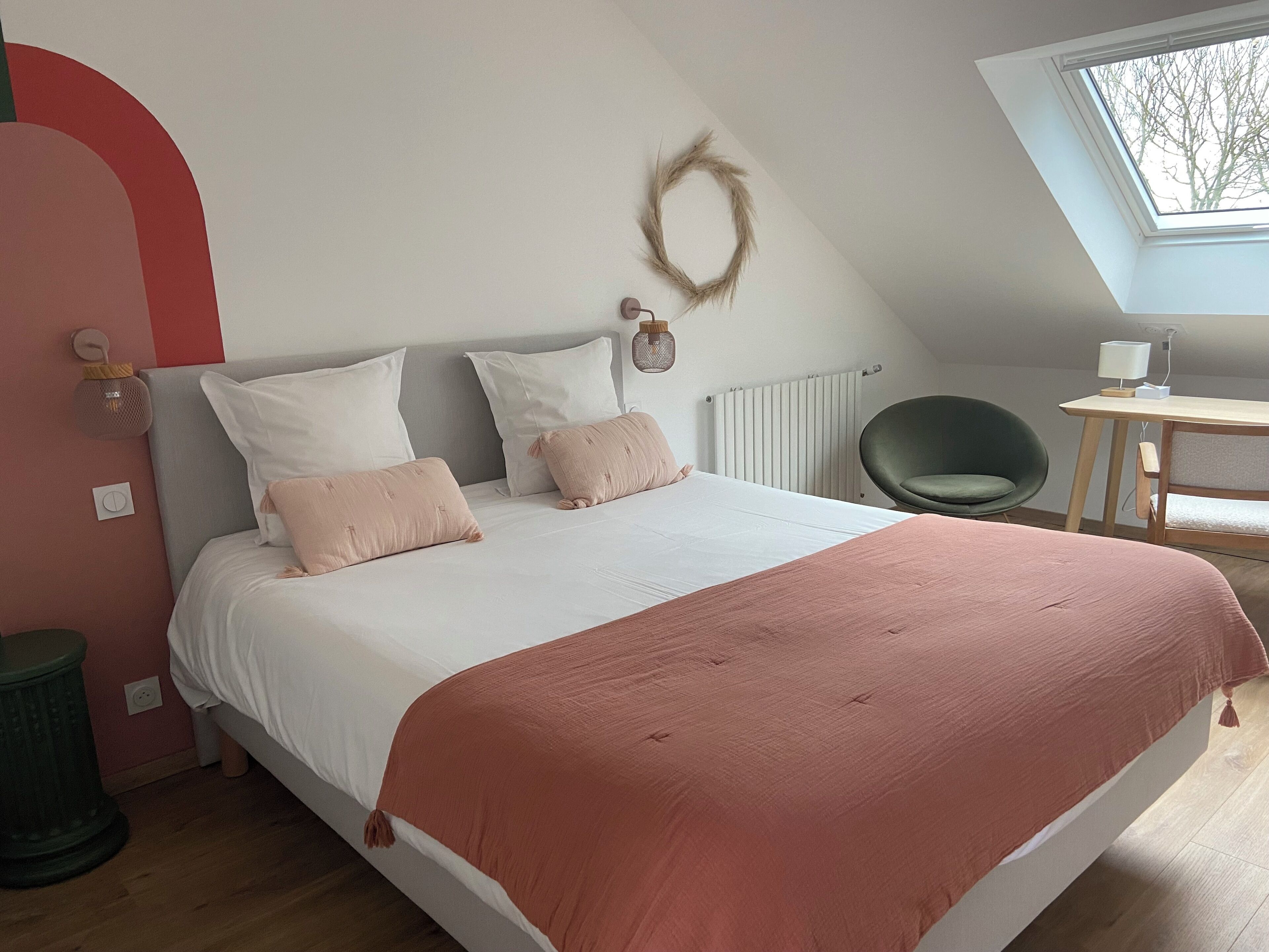 A bedroom with a bed, a desk, a chair, a radiator, and a window.