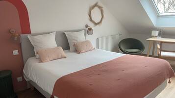 A bedroom with a bed, a desk, a chair, a radiator, and a window.