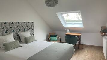 A bedroom with a bed, a desk, a chair, and a skylight.