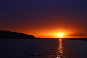 A sunset over a calm body of water with a silhouette of a hilly landscape. -  Delta Nature Resort (Somova)