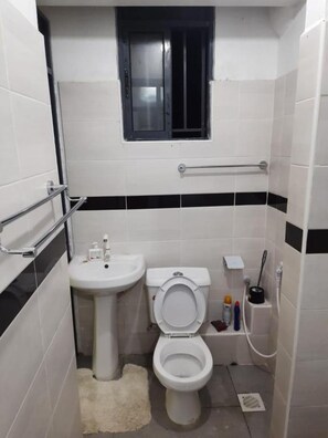 A small bathroom with a toilet, sink, and window.