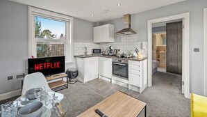 A modern kitchen with white cabinets, a microwave, and a TV displaying 'NETFLIX'.