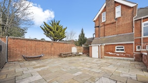 A courtyard with a brick wall, a wooden bench, and a picnic table. - Luxurious Spacious Flat Maidstone with parking (Maidstone)