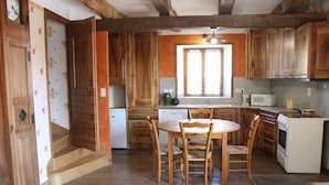 Eine Küche mit Holzschränken, einem Esstisch mit Stühlen, einer Mikrowelle und einem Spülbecken.