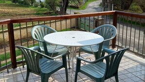 Ein runder Tisch mit vier Stühlen auf einer gefliesten Terrasse, mit Blick auf eine Wohnstraße und Häuser.