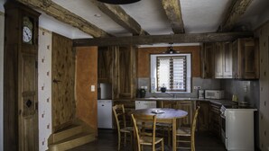 Eine Küche mit Holzschränken, einem Esstisch mit Stühlen, einem Kühlschrank und einer Uhr an der Wand.
