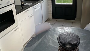 Une cuisine moderne avec des meubles blancs, un plan de travail noir et un coin repas comprenant une table ronde et des chaises.