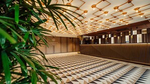 A modern reception area with a geometric patterned floor, wooden reception desk, and ceiling lights. - Elements Hotel Spa (Swieradow-Zdroj)
