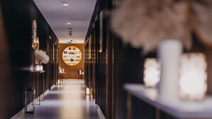 A modern hotel corridor with a central circular light fixture, a reception desk, and a white reception area. - Elements Hotel Spa (Swieradow-Zdroj)