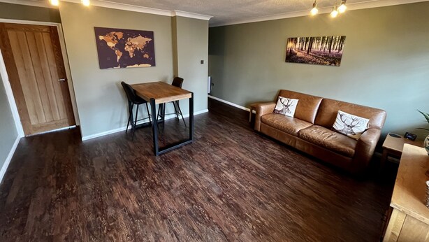 Uma sala de estar com uma mesa de jantar de madeira, um sofá de couro e um mapa-múndi na parede.