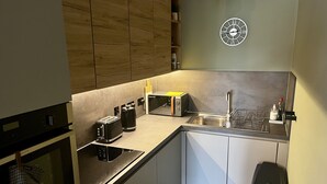 Uma cozinha moderna com forno embutido, torradeira, pia e um relógio na parede.