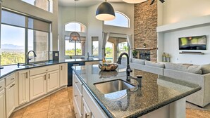 A modern kitchen with a large island, white cabinetry, and a stone accent wall. - Spa, Putting Green! Family Haven in Fountain Hills (Fountain Hills)