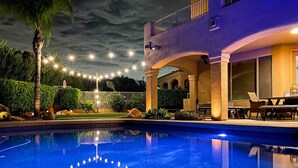 A pool with a clear reflection, a two-story building with balconies, and string lights in the background. - Spa, Putting Green! Family Haven in Fountain Hills (Fountain Hills)