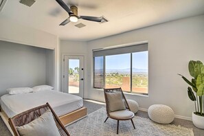 A bedroom with a bed, a chair, a large window, and a ceiling fan. - Spa, Putting Green! Family Haven in Fountain Hills (Fountain Hills)