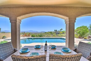 An outdoor patio with a pool, wicker furniture, and a table set for two with wine glasses and plates. - Spa, Putting Green! Family Haven in Fountain Hills (Fountain Hills)