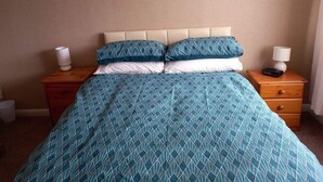 A bedroom with a bed, two nightstands, and two wall-mounted lamps.