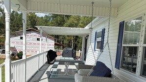 A covered porch with a swing chair, a table, and a ceiling fan. - Lake Murray Lake Views Galore (Prosperity)