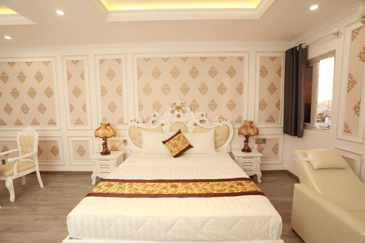 Ein geräumiges Schlafzimmer mit einem großen Bett, zwei Nachttischen mit Lampen, einem Sessel und einem Massagetisch.
