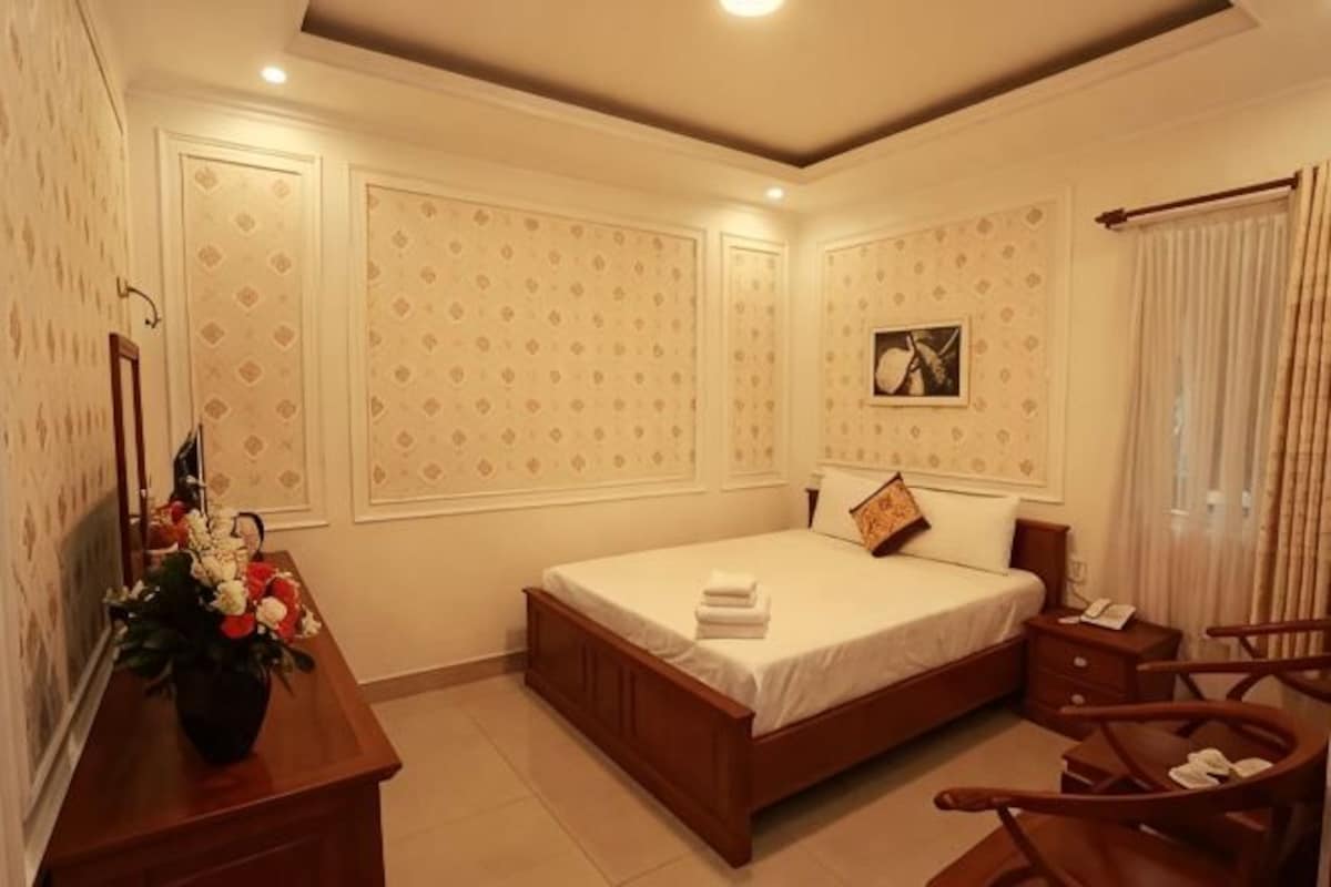 Une chambre à coucher avec un lit, des tables de chevet, un bureau et une chaise.