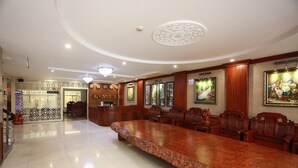 Amplia sala de conferencias con una larga mesa y varias sillas, un área de recepción con mostrador y decoración en las paredes.