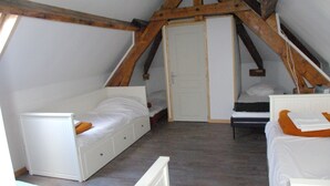 A small, attic-style bedroom with two beds, wooden beams, and a white door. - 2 gîtes groupable from 4 to 15 pers for 2- 4 -6 to 32 pers 15km from ARRAS (Arras)